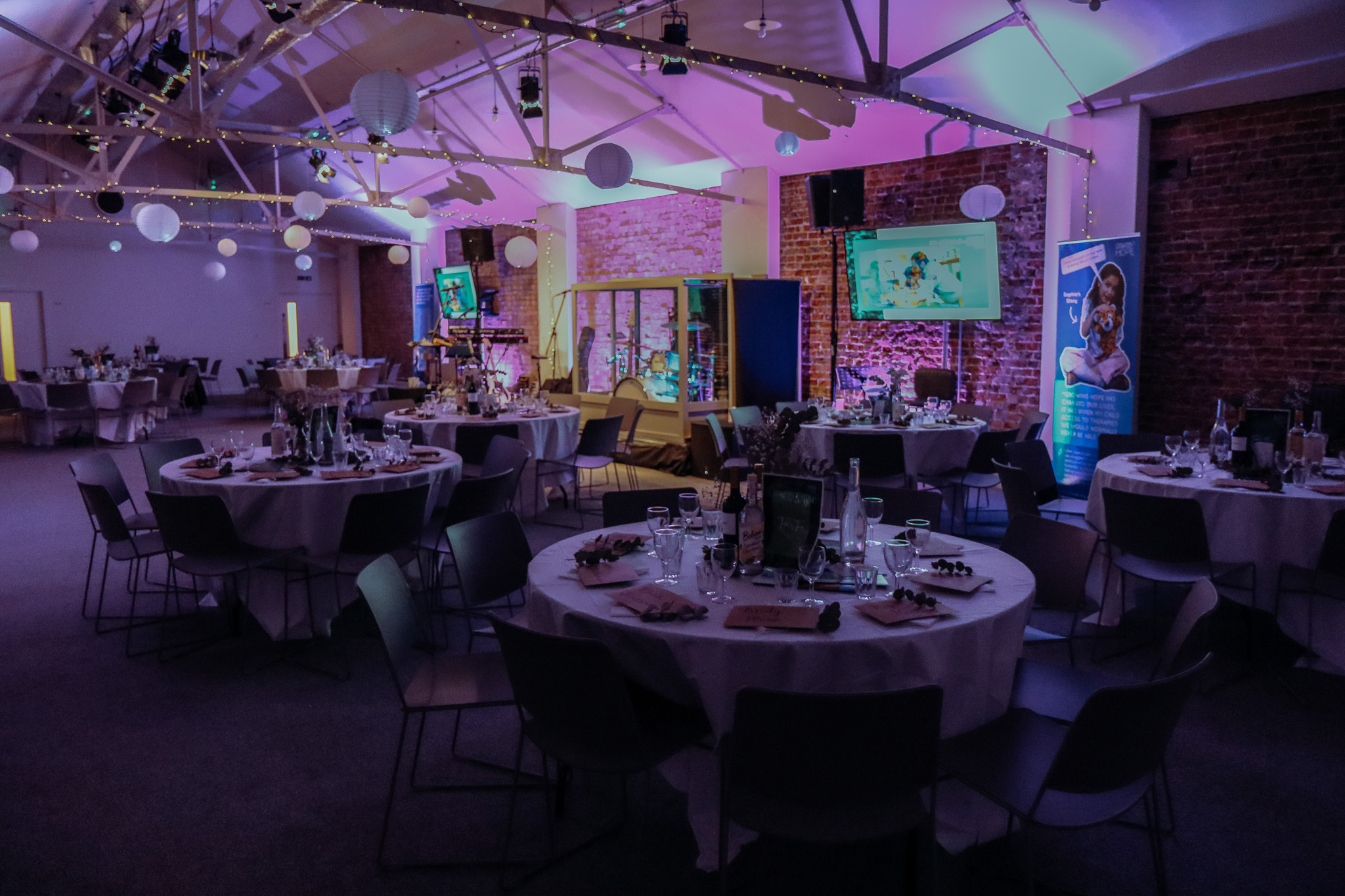 Networking charity fundraiser in a stylishly decorated event space with round tables.