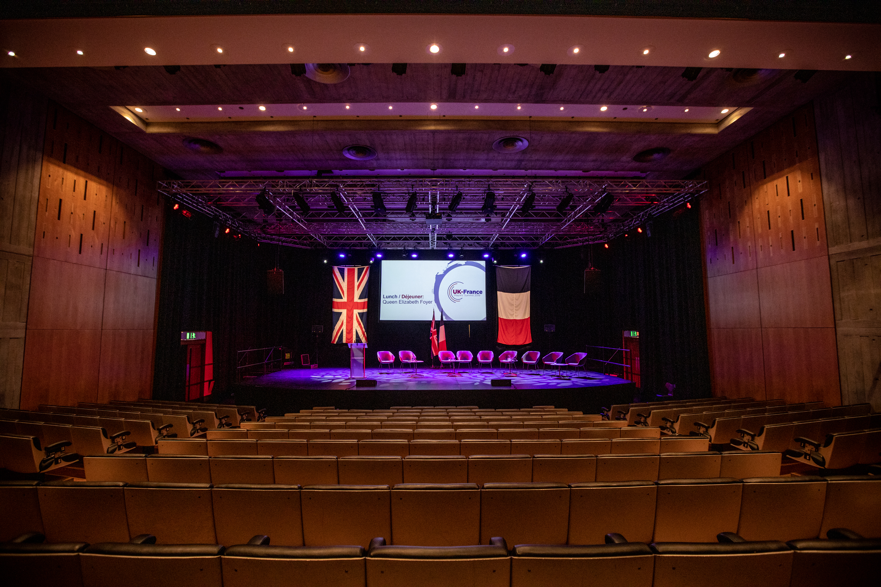 Purcell Room conference setup with stage, seating, and presentation screens.