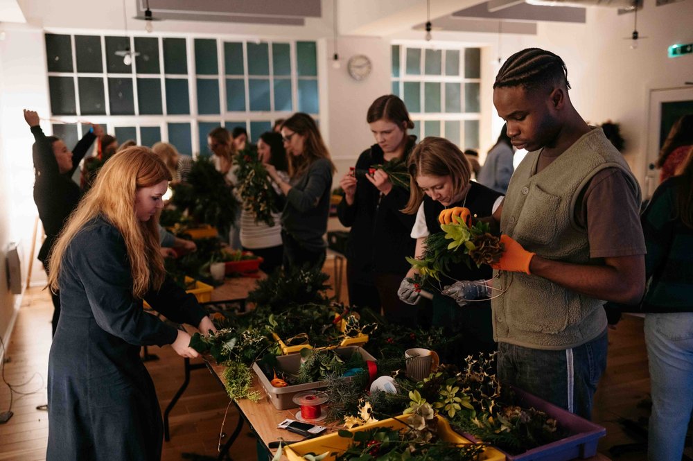 Workshop participants engaged in floral arrangement at King's House for team-building event.