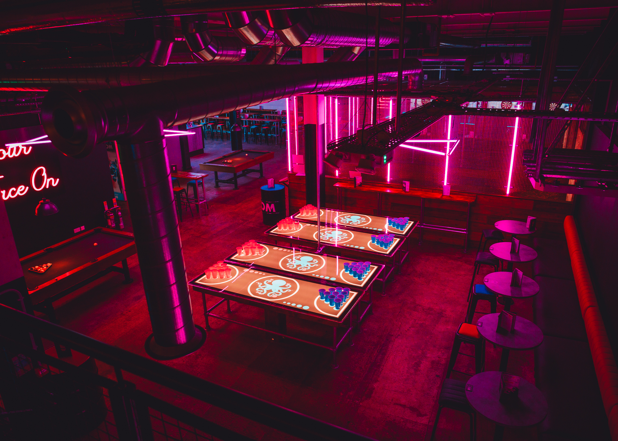 Exclusive private hire event space in Boom Battle Bar Leeds with neon lighting and game tables.