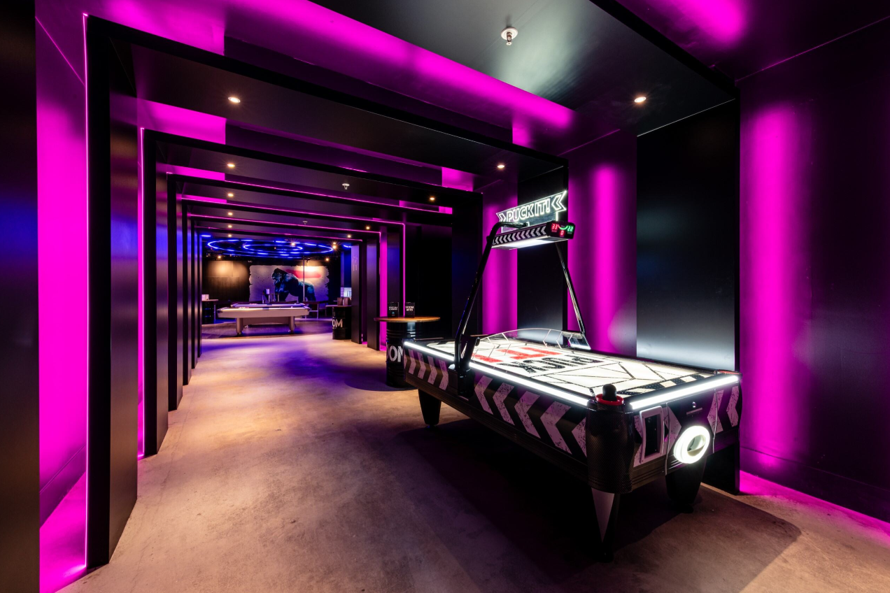Modern event space with purple lighting and air hockey table for corporate parties.