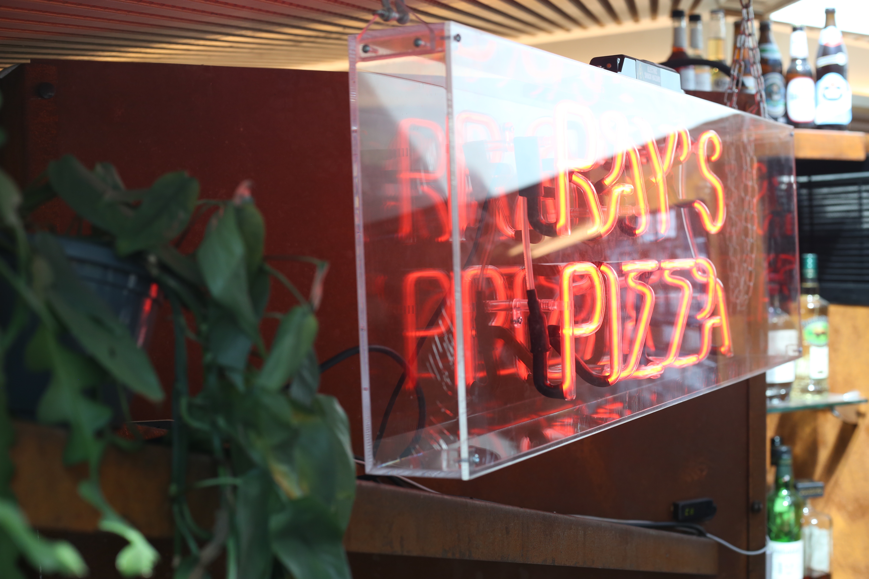 Vibrant neon pizza sign at Aldgate Tap, ideal for casual gatherings and networking events.