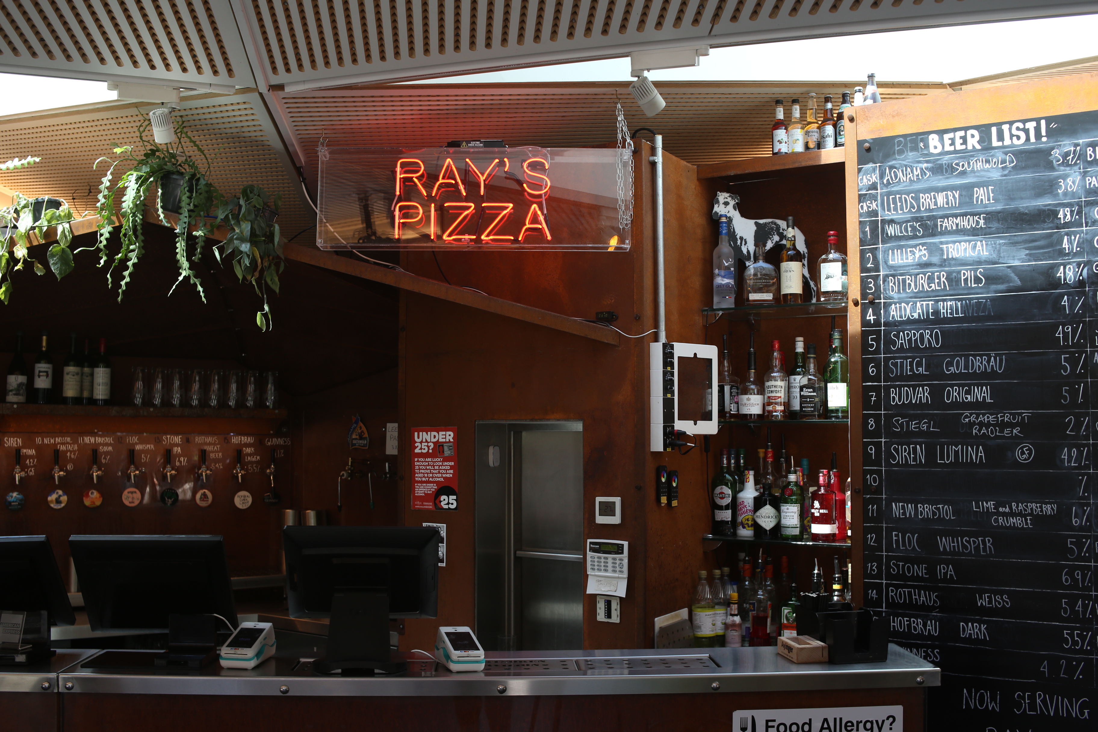 Vibrant Aldgate Tap bar with neon "Ray's Pizza" sign, ideal for casual events and networking.