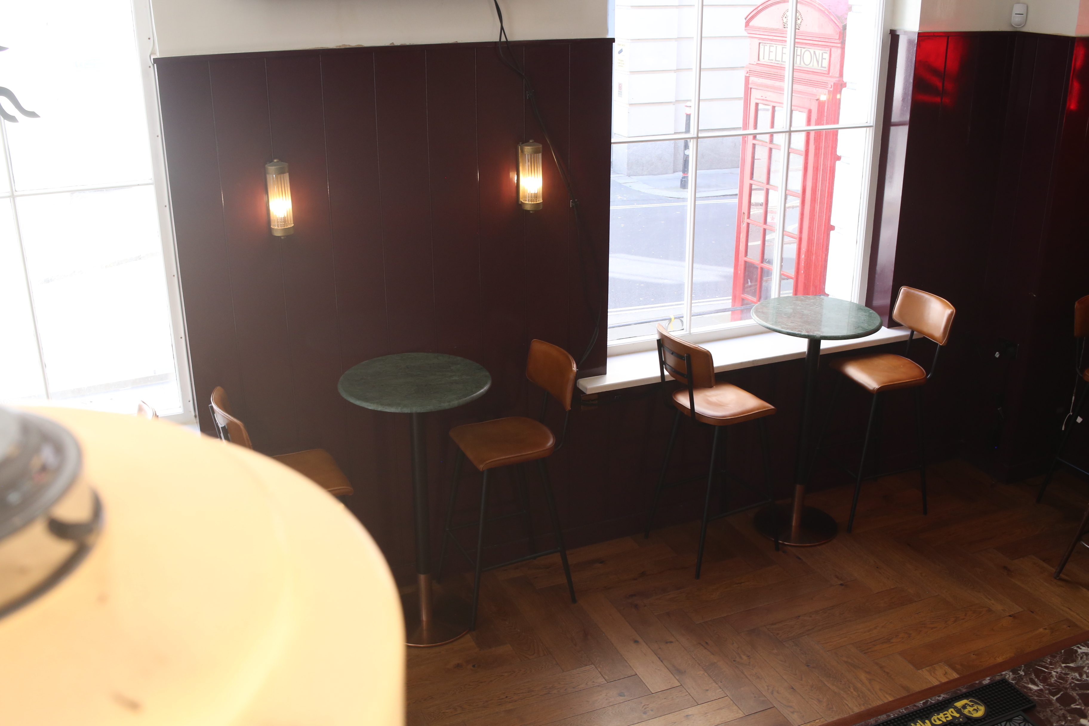 Chic venue with high tables for informal networking near iconic red telephone booth.