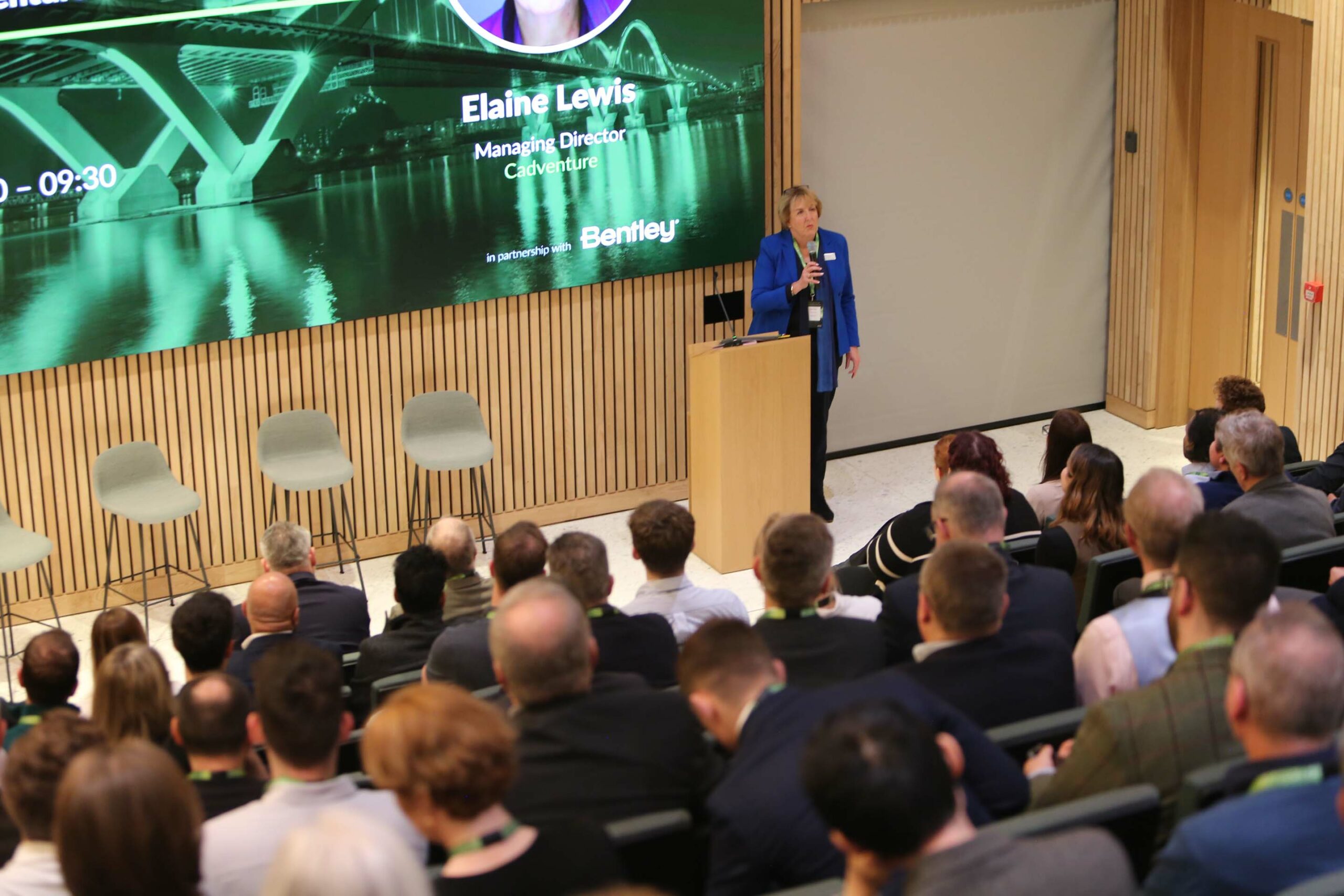 Professional speaker on stage in modern event space at 8 Bishopsgate corporate event.