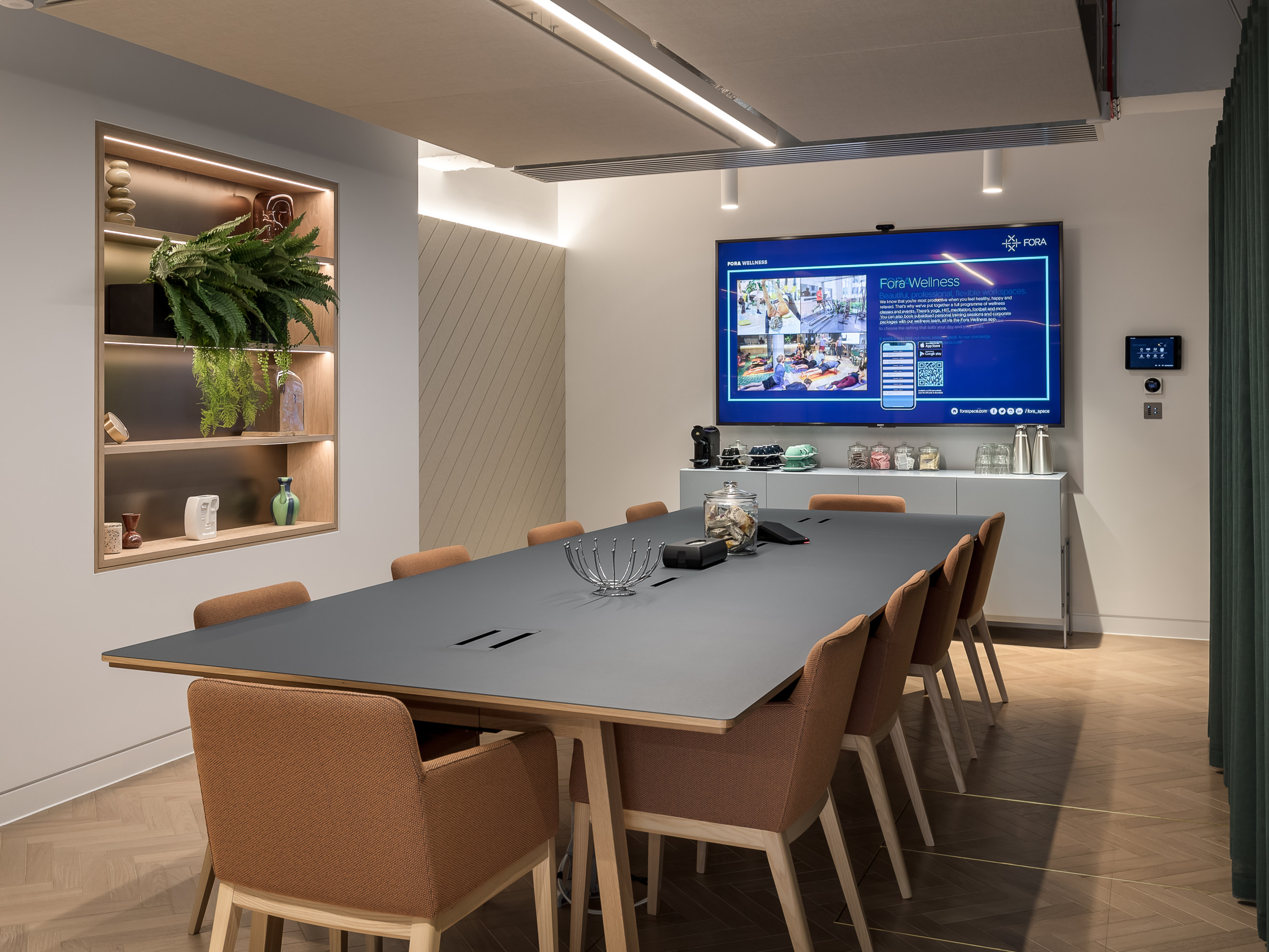 Modern meeting room with sleek table and large screen for collaborative sessions.