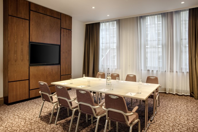 Raglan Suite meeting room in Leonardo Hotel Cardiff with large table and natural light.