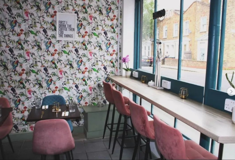 Vibrant meeting space at Audrey's Jamaican Restaurant with floral wallpaper and communal table.