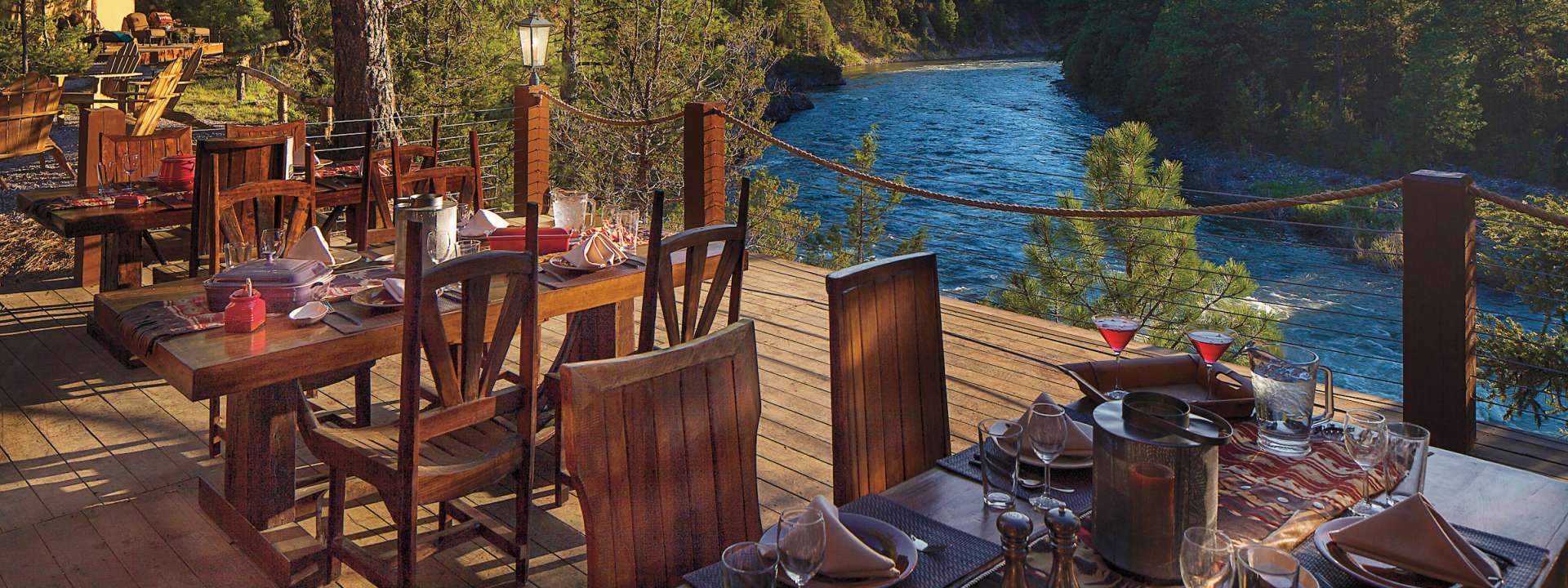 Outdoor dining at Bull Pen Patio, rustic tables by serene river for retreats and gatherings.