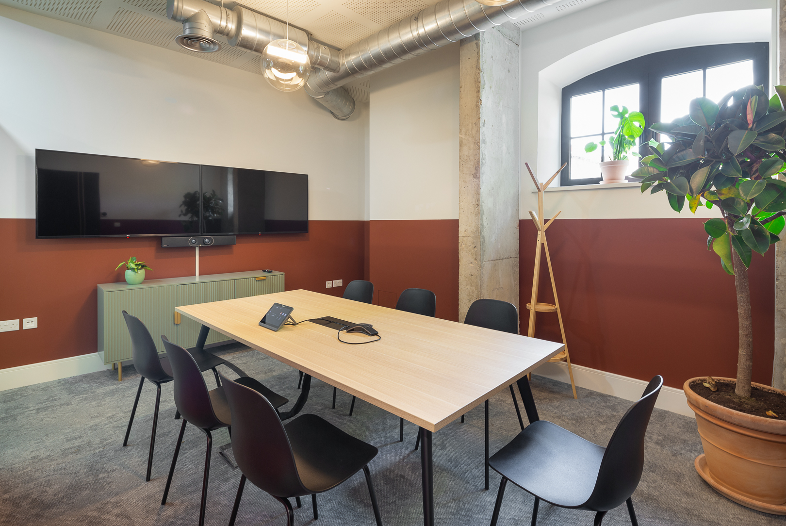 Modern meeting room with large table and dual screens for collaboration at Riley Studios.