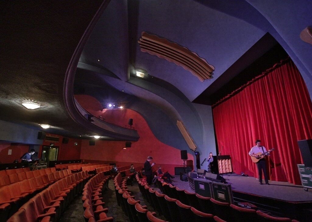Vibrant Rio Cinema Screen Room with red curtain for concerts and events.