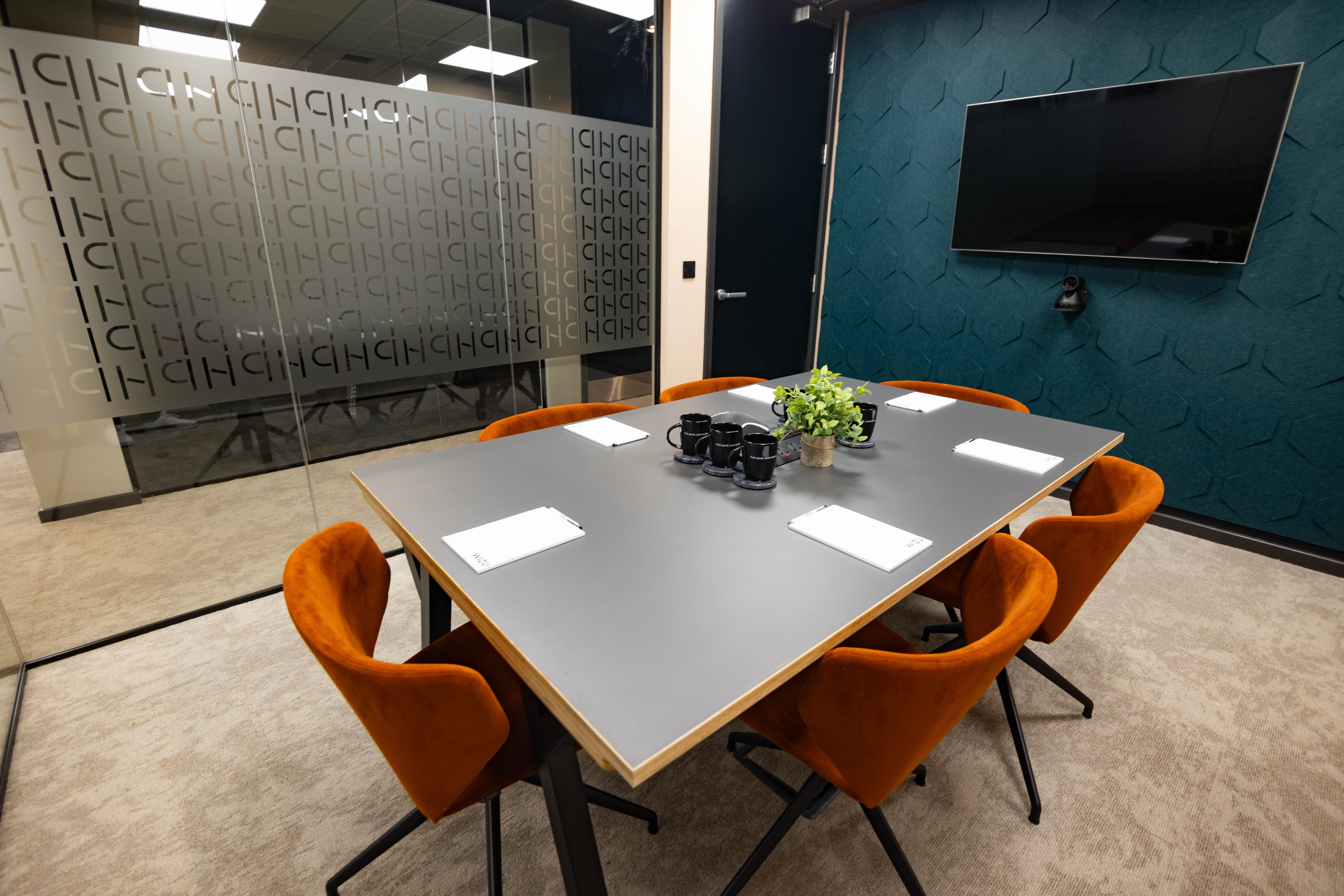 Modern conference room with gray table and orange chairs for professional meetings.