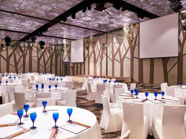 Elegant event space with round tables, blue glassware for conferences and banquets.