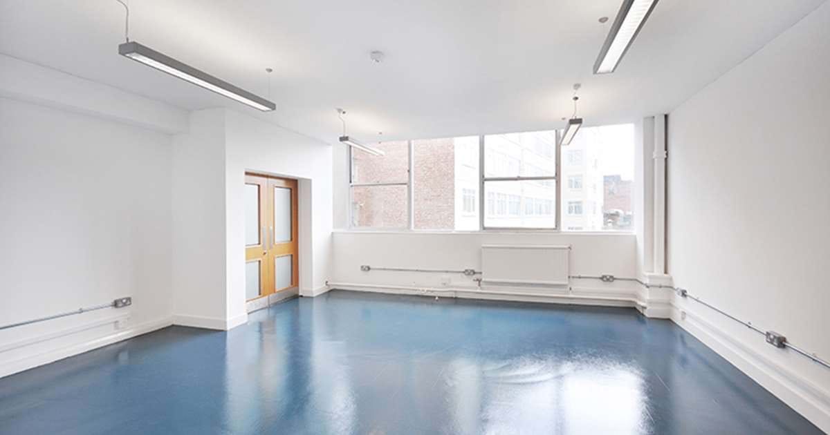 Blank event space with large windows, ideal for workshops and networking events.