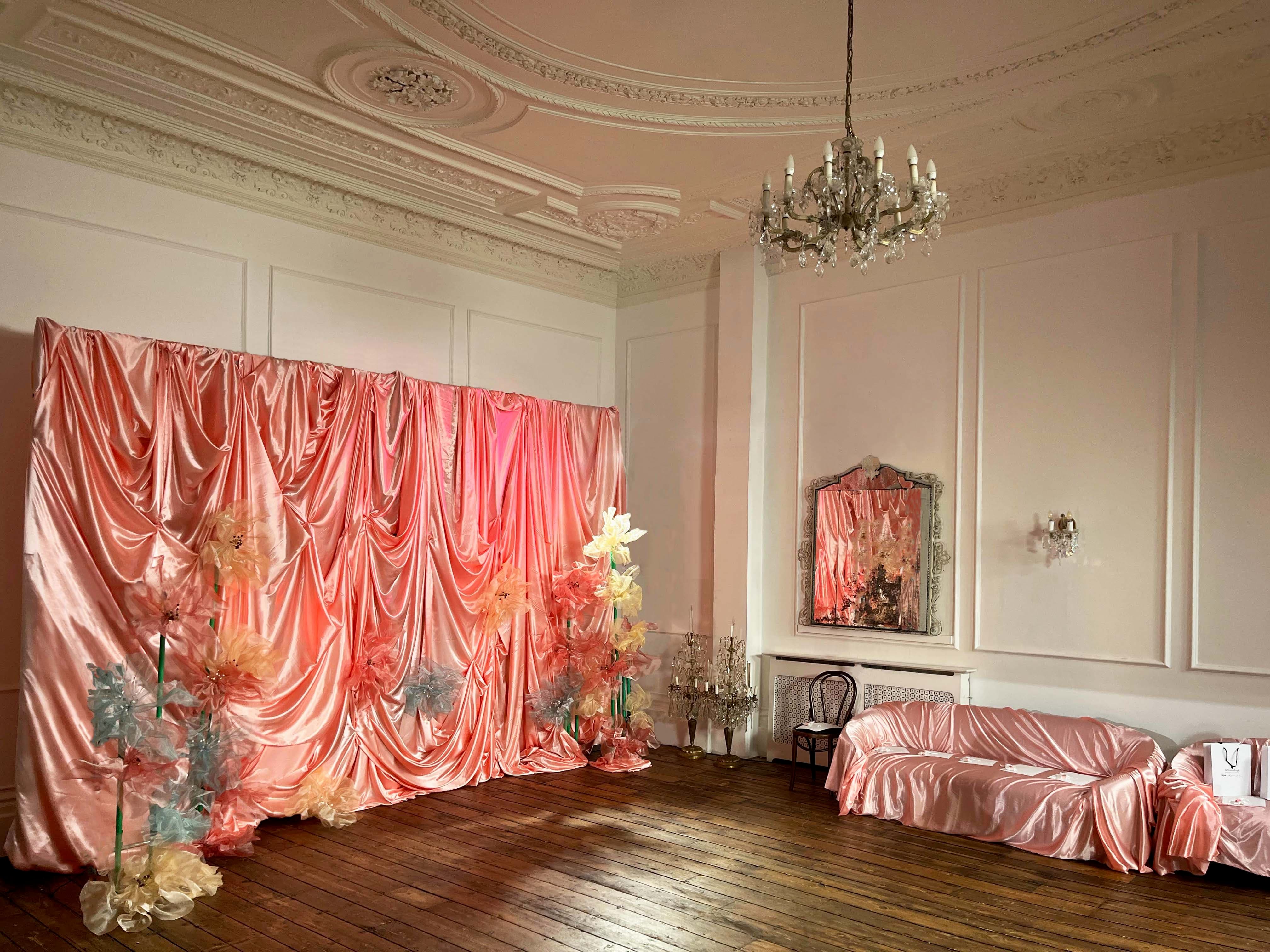 Elegant event space with peach drapery and chandelier, perfect for gatherings or photoshoots.