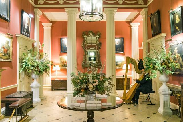 Elegant event space with red walls, floral displays for gala networking at Courteenhall Estate.