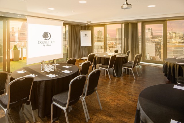 Sky Lounge meeting room with round tables and large windows at DoubleTree Manchester.