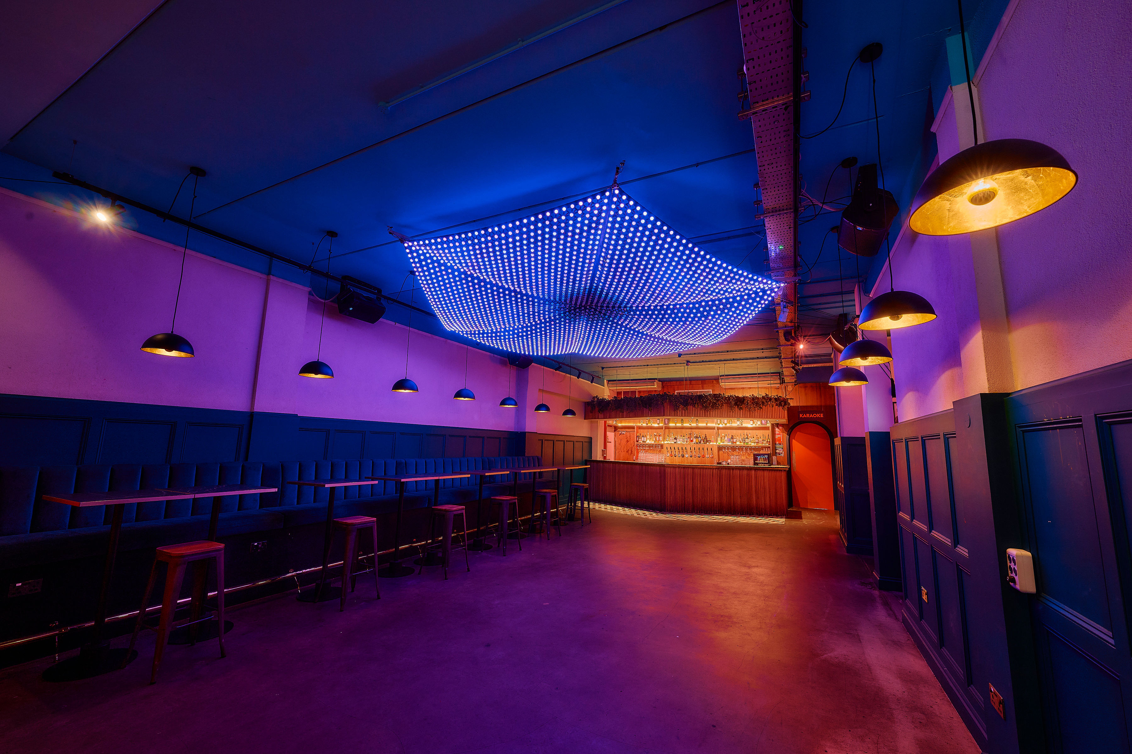 Modern event space at Colours Hoxton with vibrant blue lighting and bar seating.