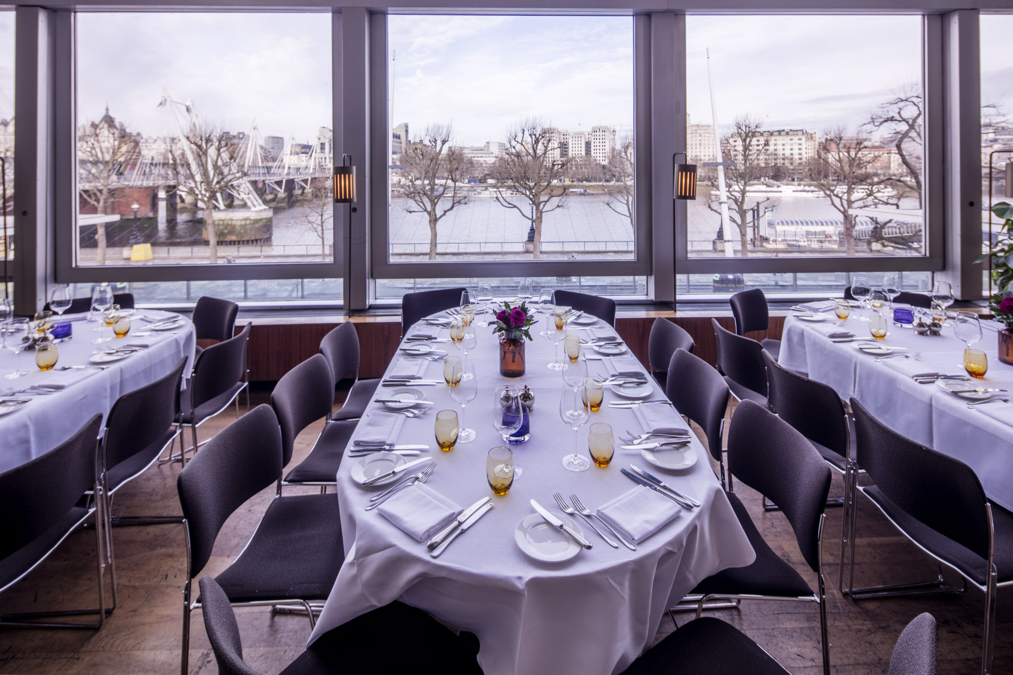 Elegant dining setup with stunning river view, ideal for corporate events and private dinners.