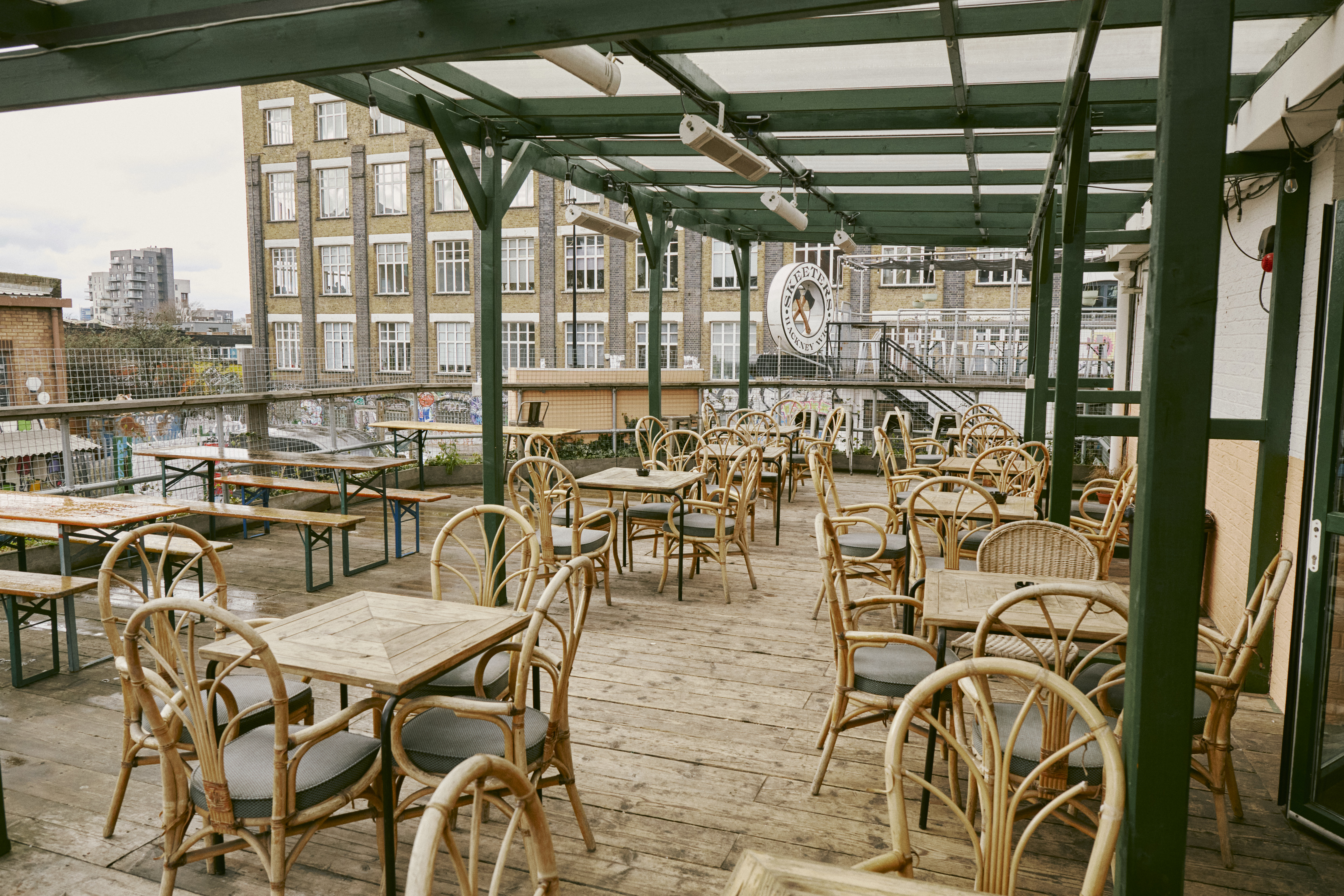 Outdoor venue in Hackney Wick with wooden tables for casual gatherings and networking events.