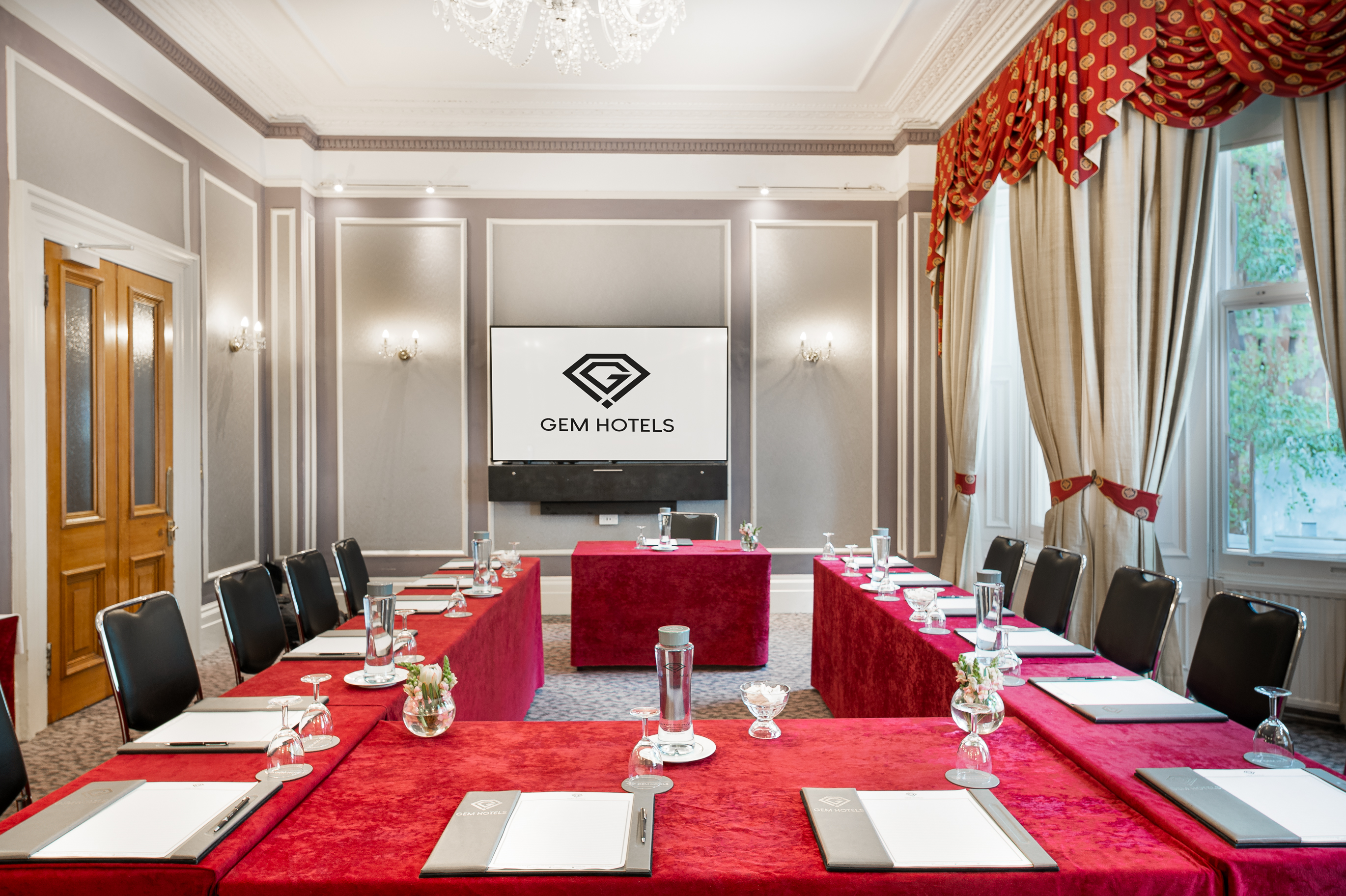 Elegant meeting room at Gem Strathmore Hotel with red and gold decor for professional events.