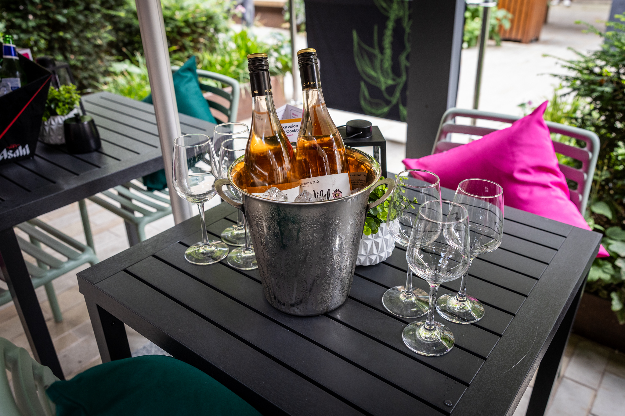 Outdoor networking event setup with stylish rosé and vibrant cushions at Lucky Voice.