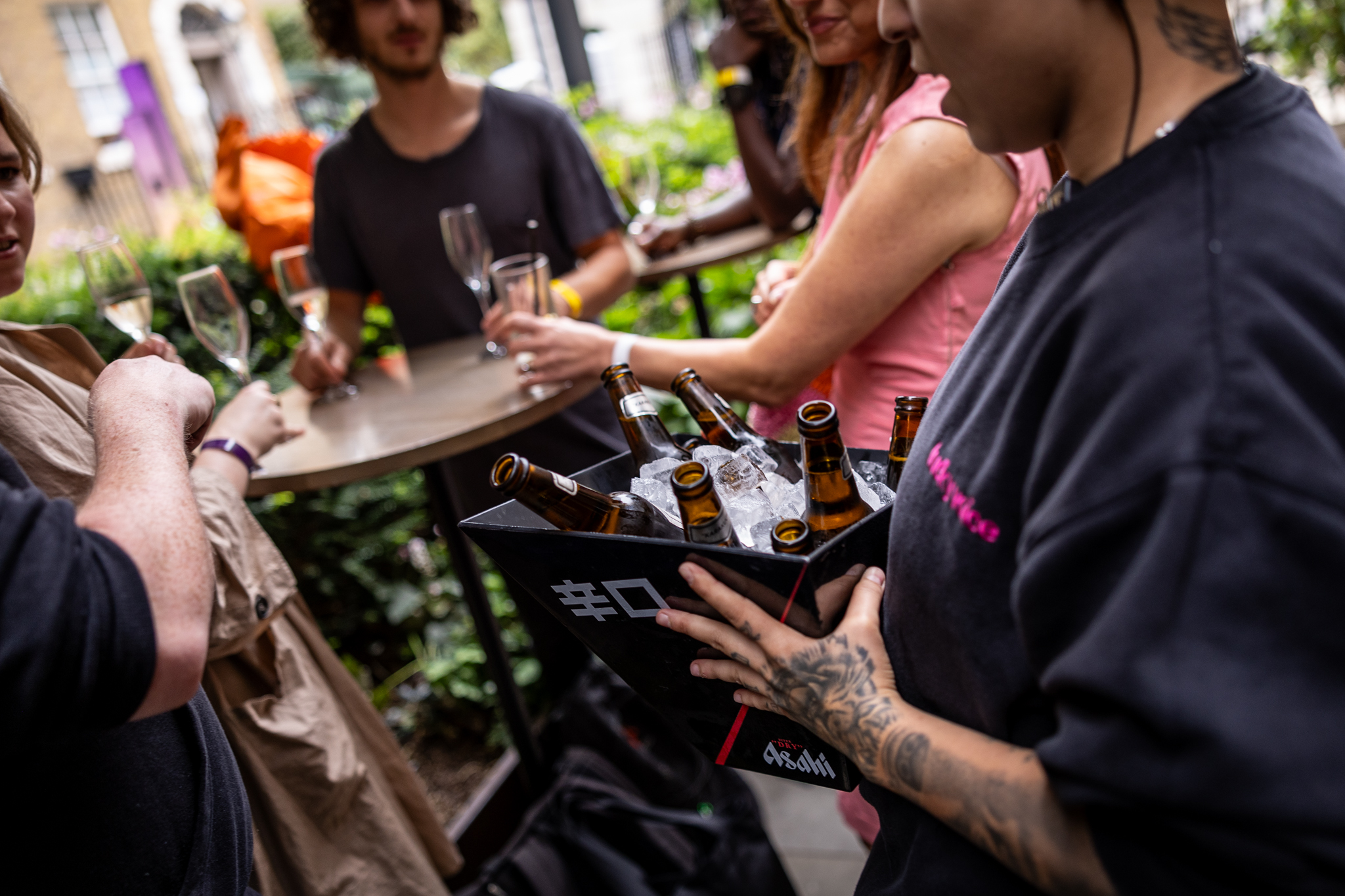 Lively outdoor networking event at Lucky Voice Liverpool Street with drinks and greenery.