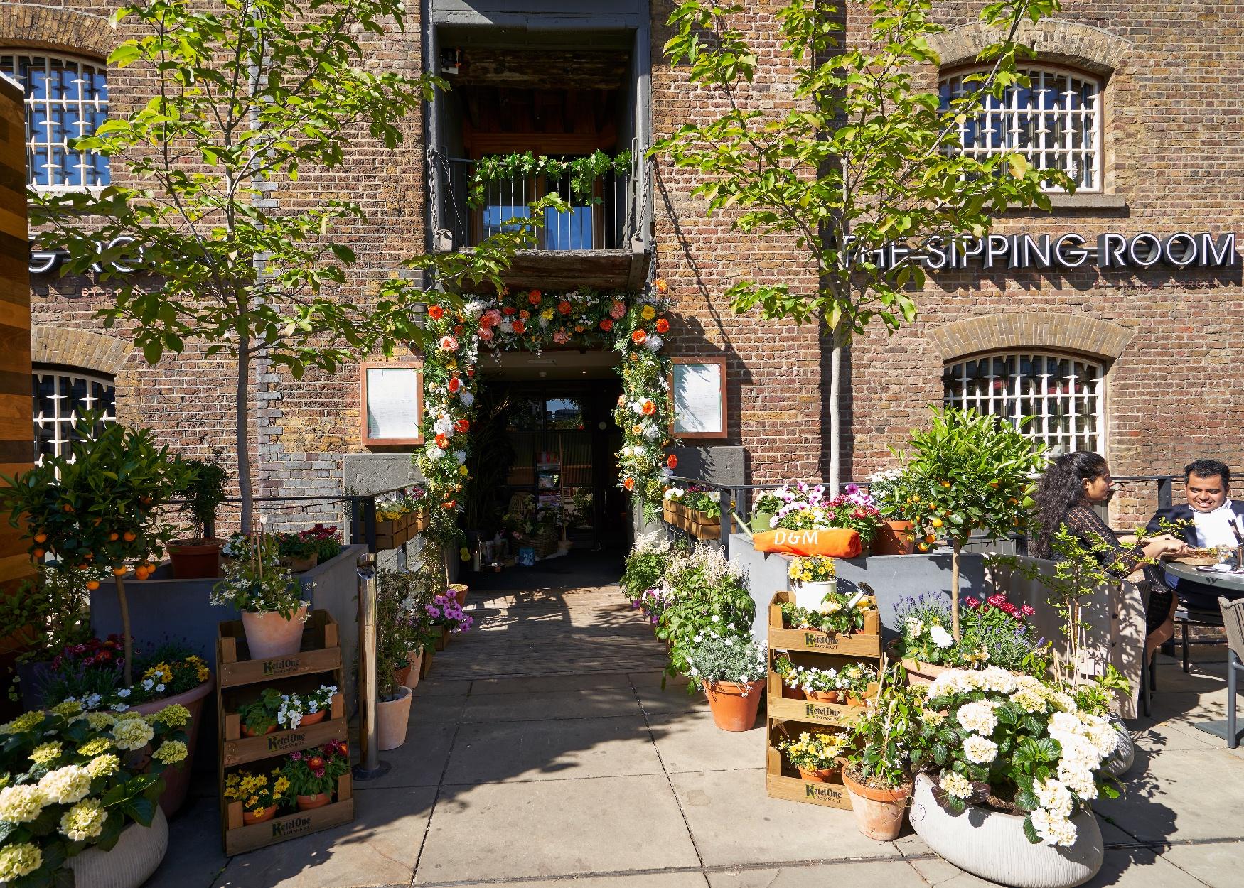 Charming outdoor venue entrance with vibrant flowers, perfect for weddings and garden parties.