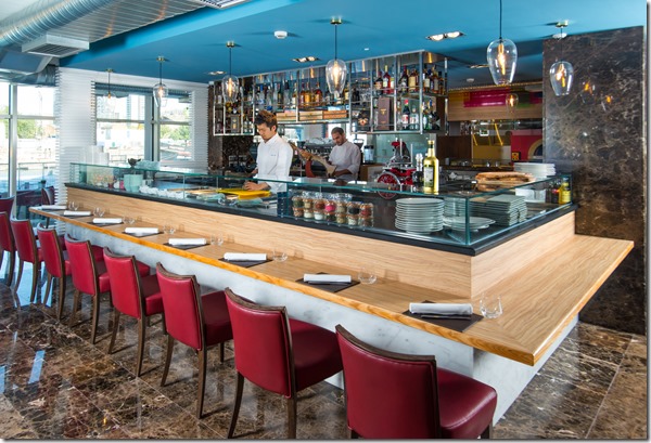 Modern restaurant with red seating and open kitchen, perfect for upscale events.