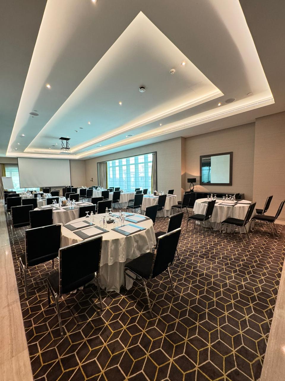 Corporate meeting room in Dammam, featuring round tables and natural light for events.