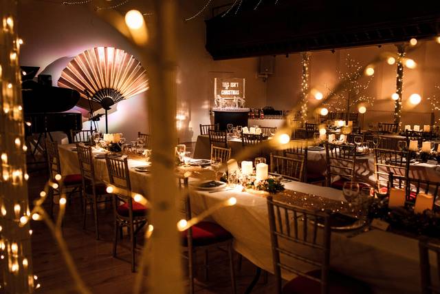 Elegant event space with set tables and string lights for sophisticated dinners or celebrations.
