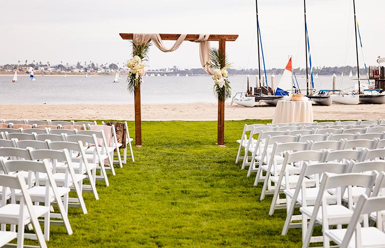 Outdoor wedding setup at Catamaran Resort with floral arch and waterfront view.