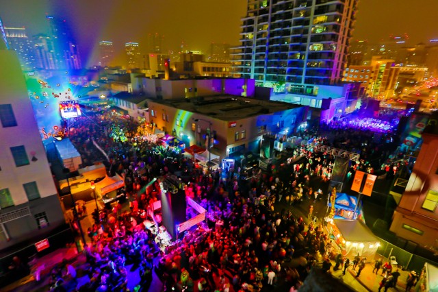 Vibrant outdoor festival with models and colorful lights in Gaslamp District.