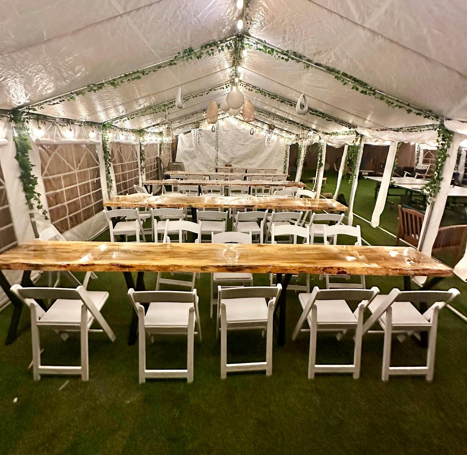 Event space with wooden tables and string lights at Good Life Vacation Rental Resort.