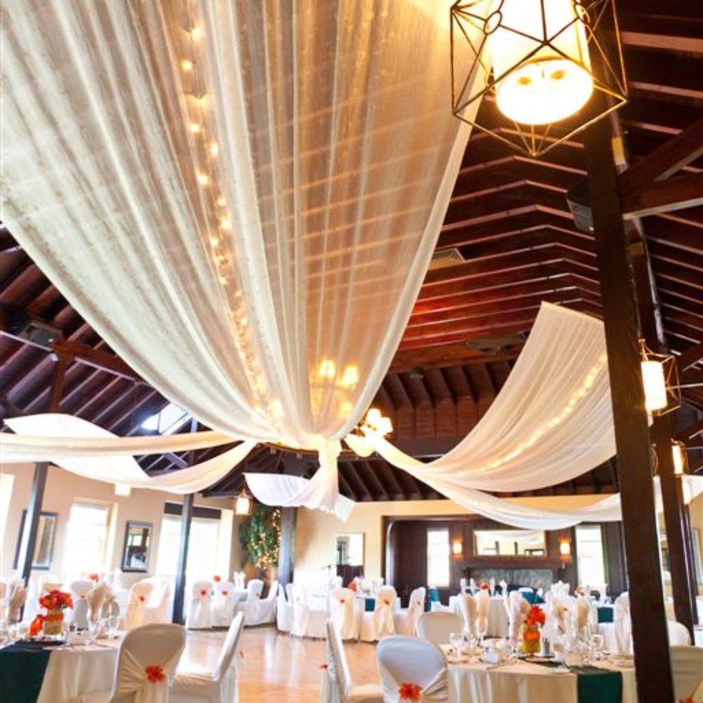Elegant indoor banquet hall with draped ceiling, perfect for weddings and upscale events.