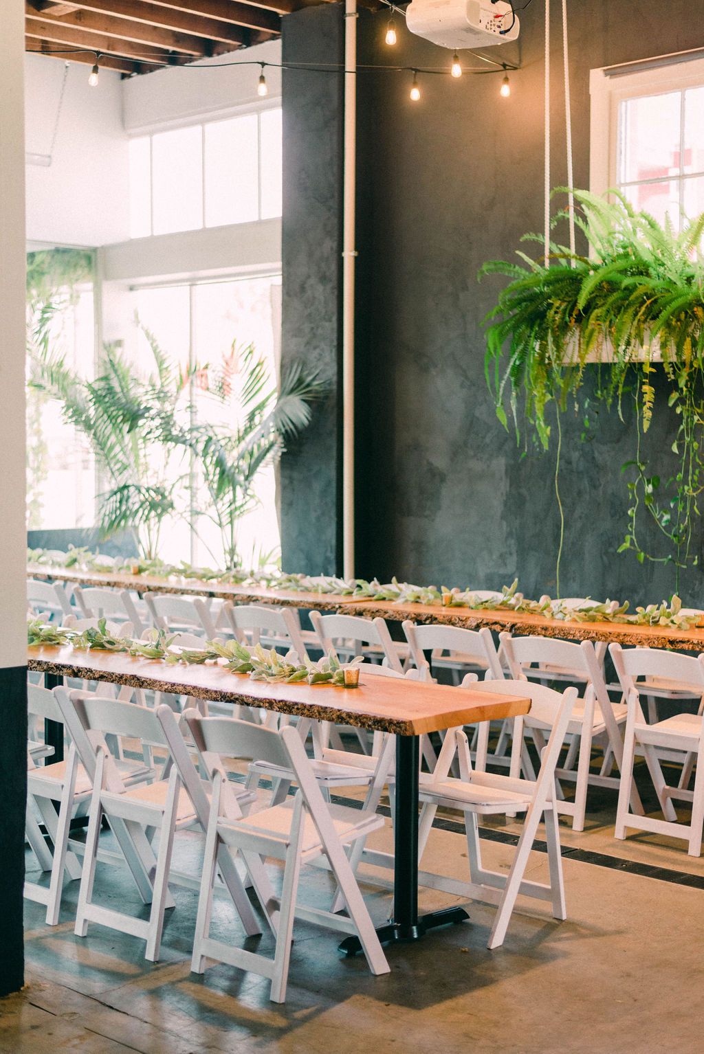Greenhouse event space with wooden tables and greenery for corporate meetings and gatherings.
