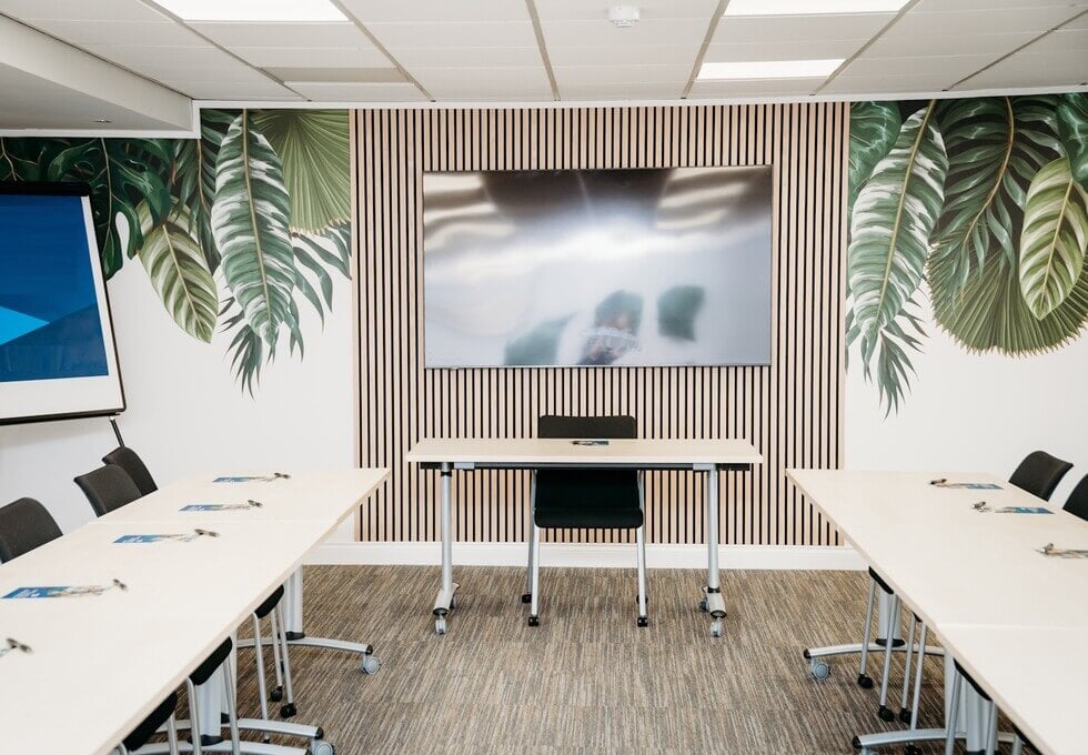Modern meeting room with flexible seating and tropical wall design for workshops.