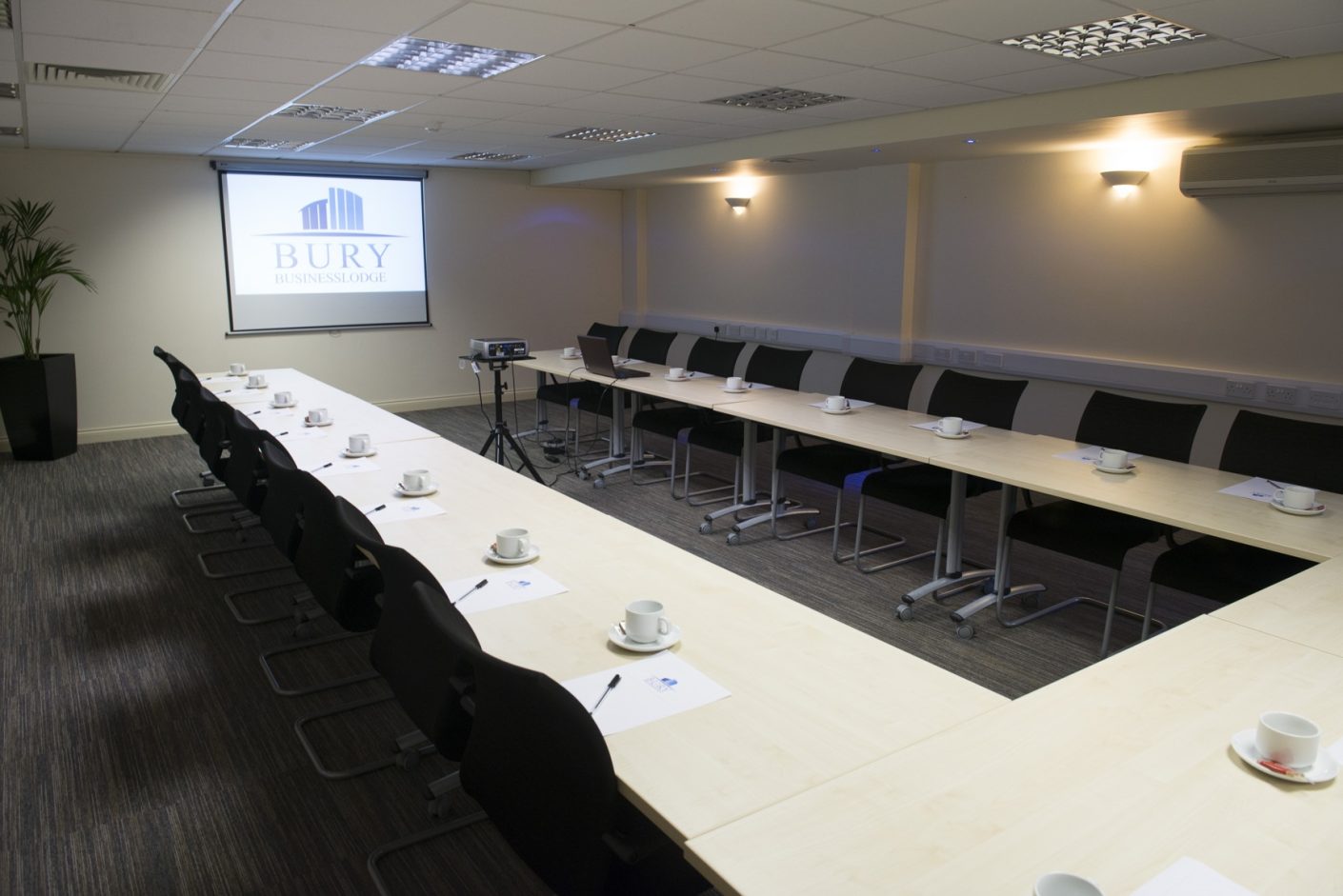 Meeting room with long table setup, projector screen for professional events.
