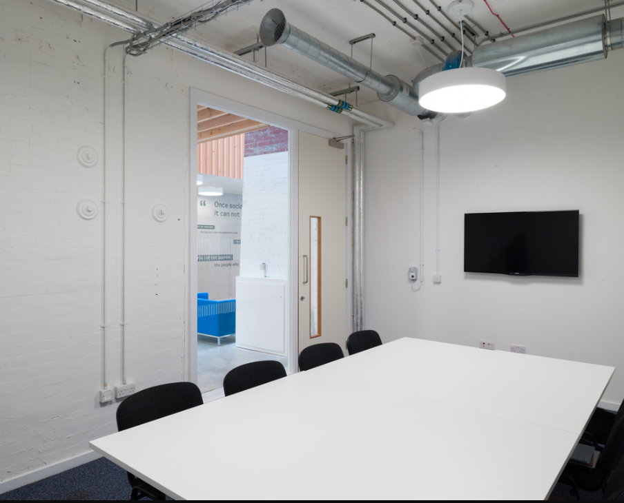 Modern conference room with white table, ideal for meetings and events.