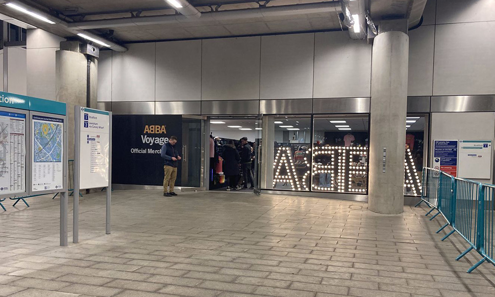 ABBA Voyage event venue entrance with illuminated sign, showcasing crowd engagement.