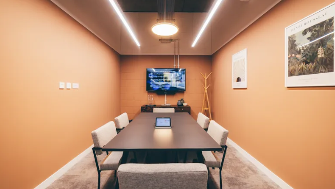 Modern meeting room in Fulham with orange walls, ideal for collaborative events.