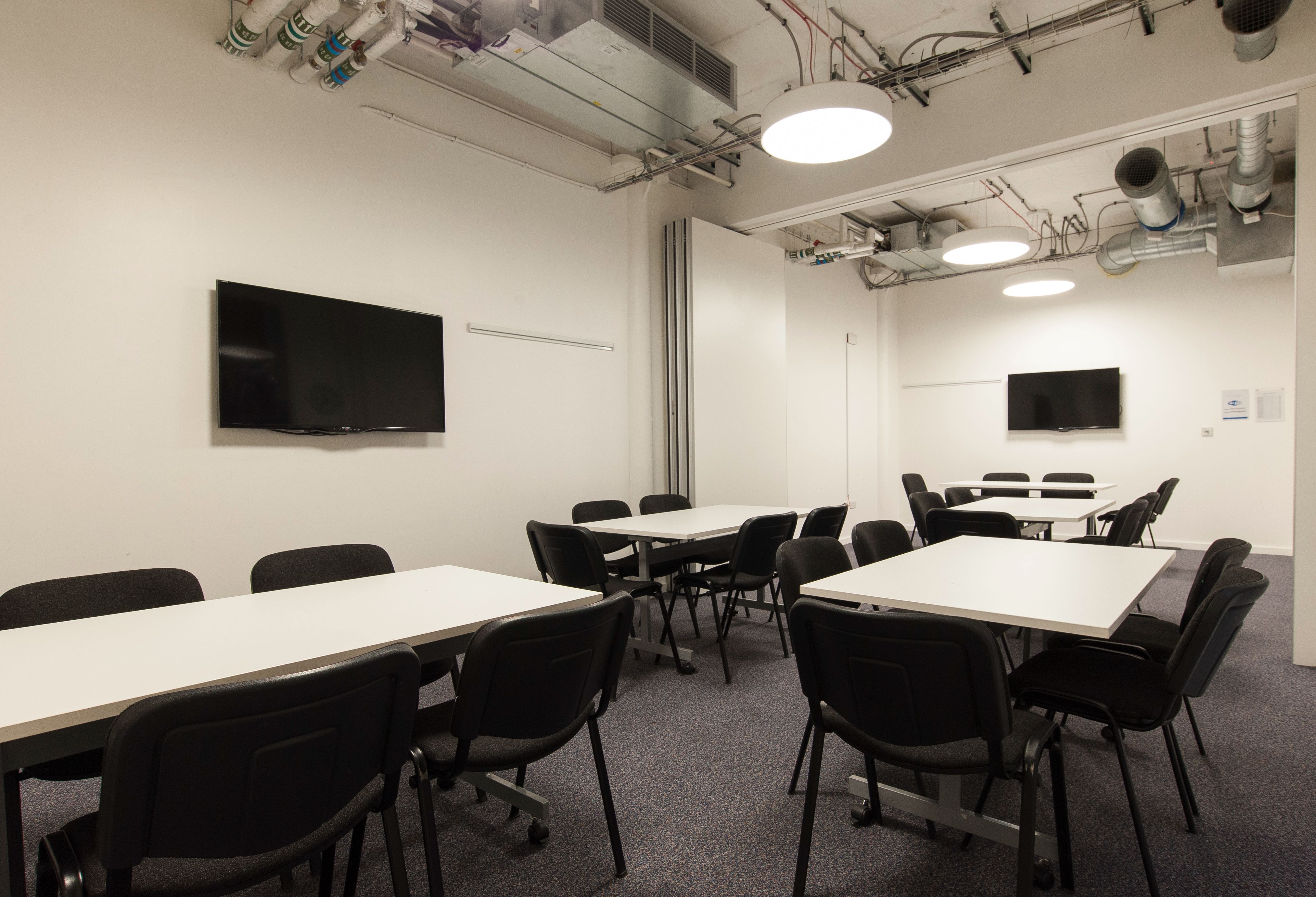 Modern meeting room with dual screens for presentations, ideal for corporate events.