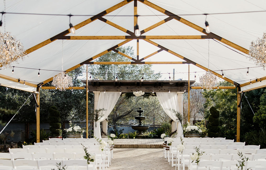 Outdoor wedding venue at Casa Bella with elegant canopy and charming fountain backdrop.