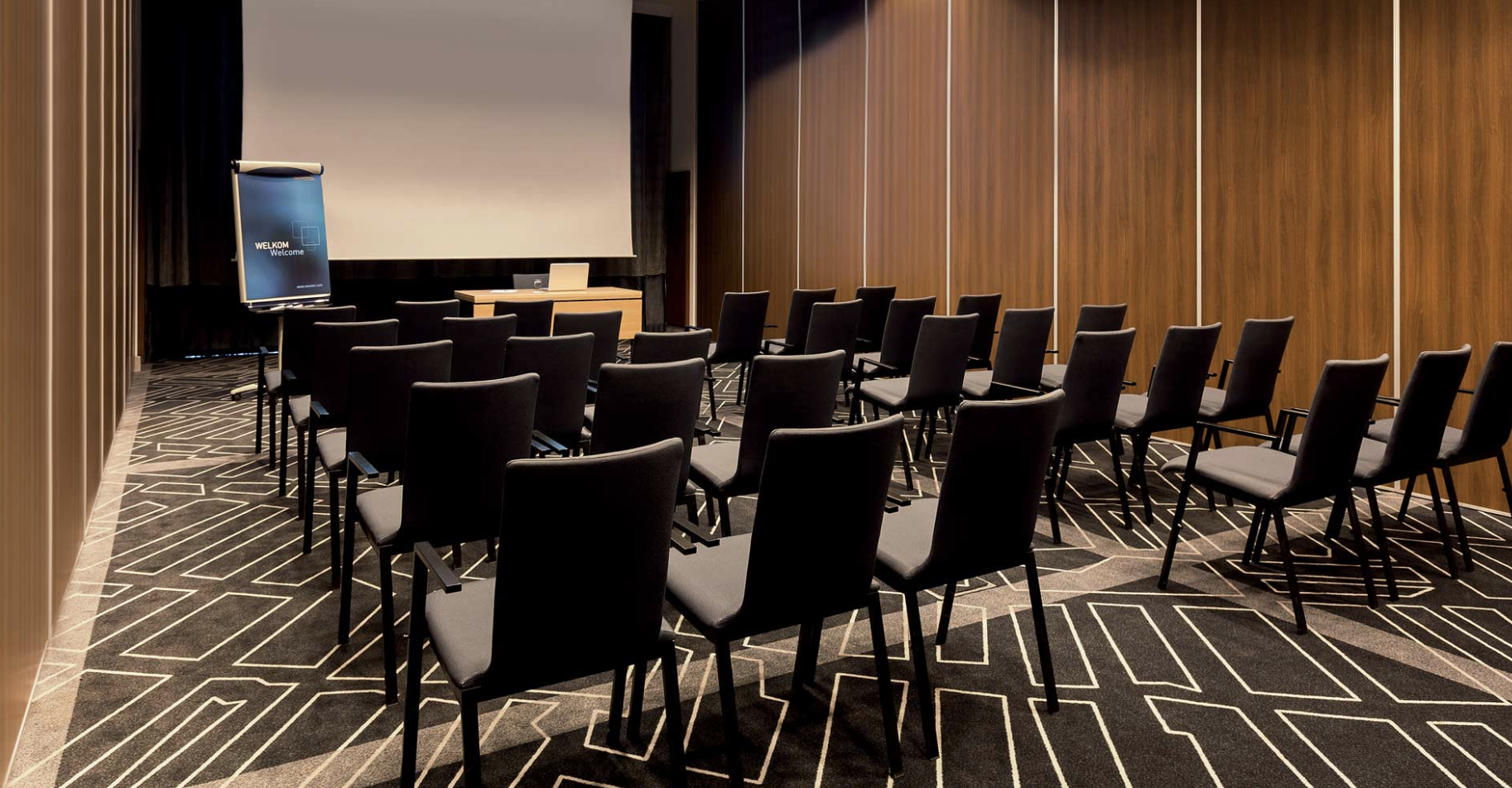 Meeting room at Hotel Novotel Amsterdam City, featuring black chairs for seminars.