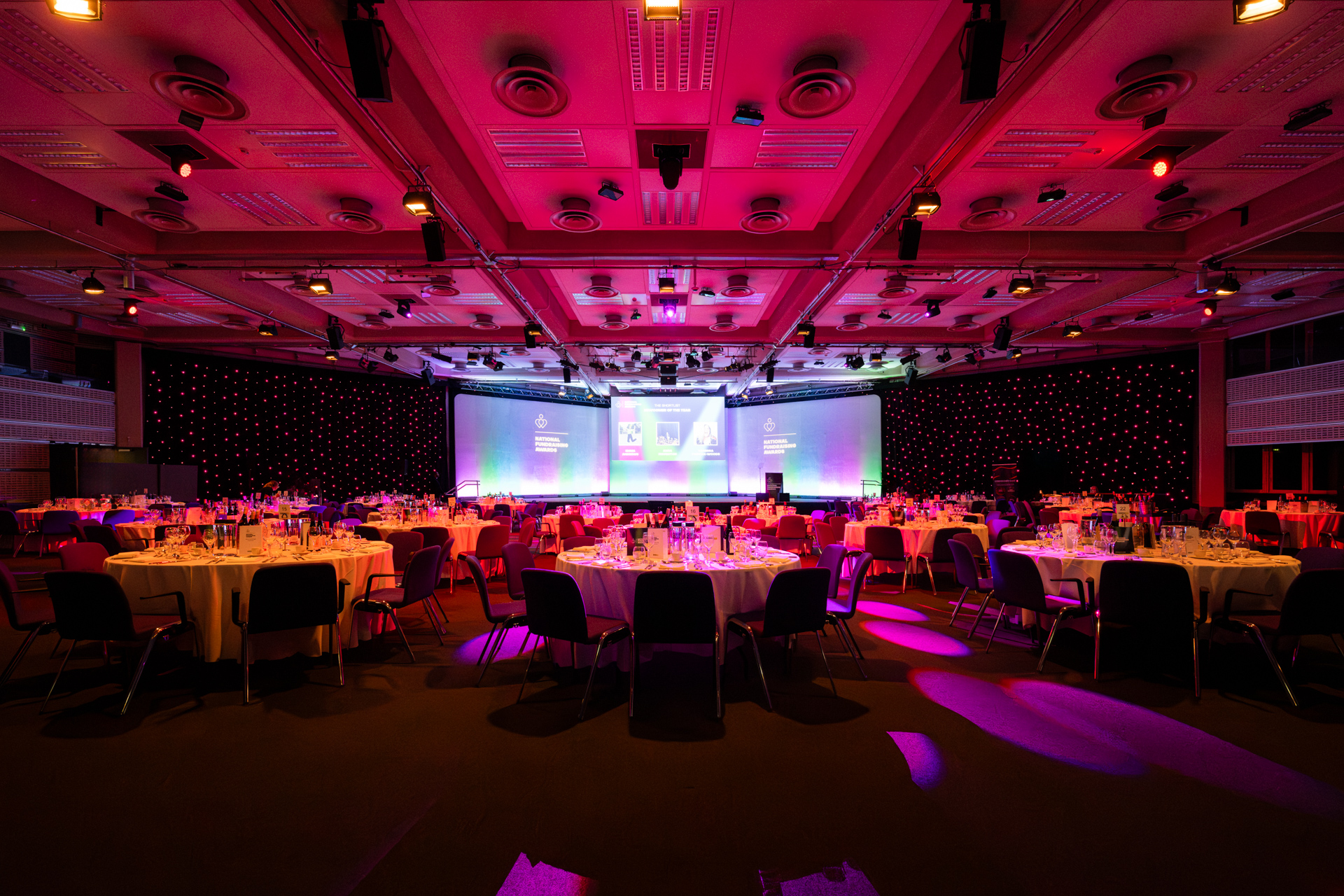 Churchill & Pickwick gala setup with elegant tables and vibrant lighting at QEII Centre.