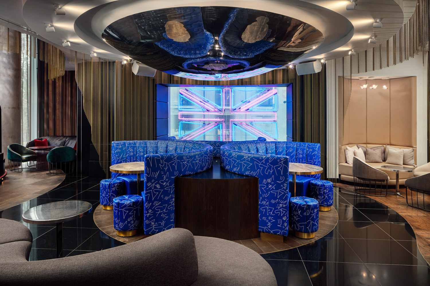 Modern meeting space in W London with blue seating and Union Jack screen for events.
