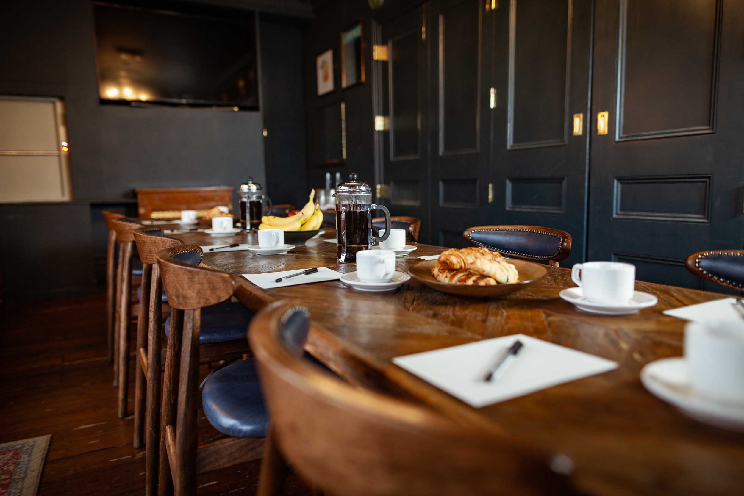 First Floor Lounge meeting space with wooden table, coffee service, and pastries.