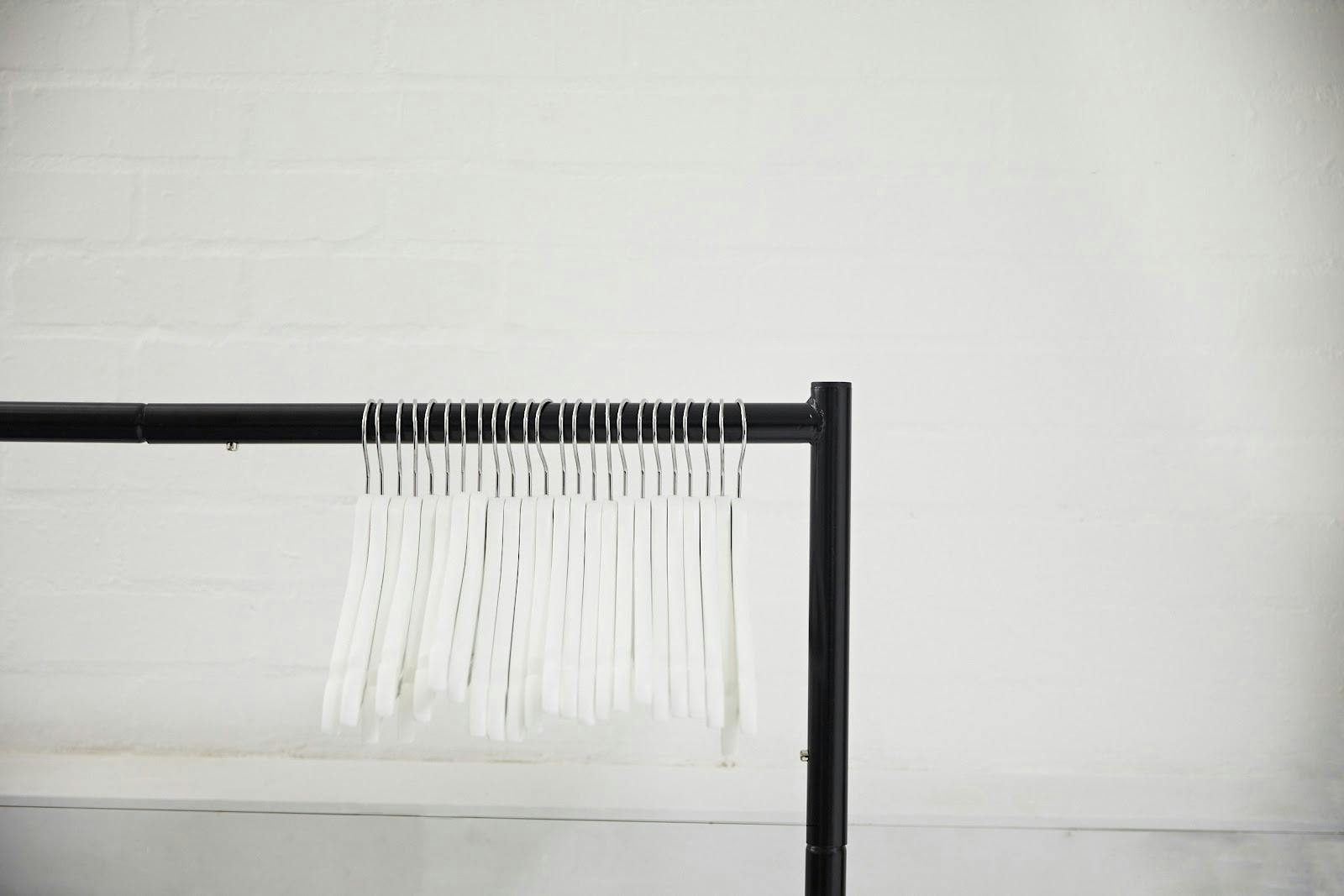 Minimalist clothing rack with white hangers for elegant fashion events and trade shows.