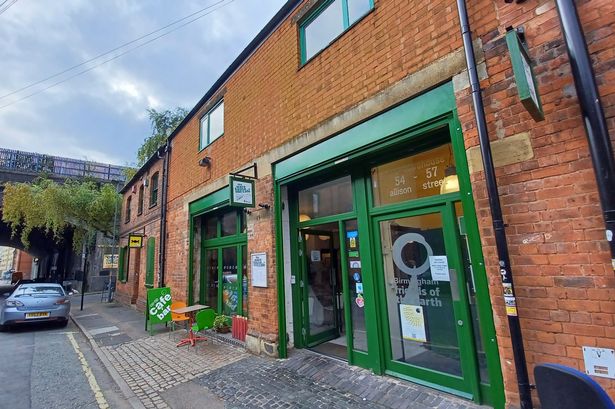 Charming cafe venue with rustic brick and green windows for creative events.