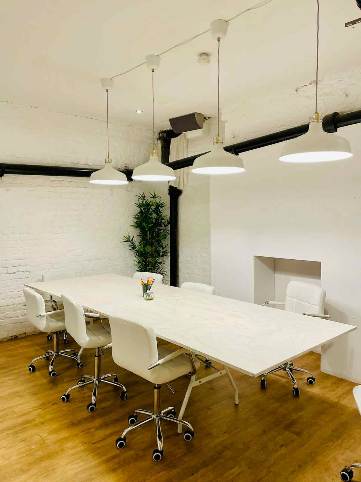 Modern minimalist meeting room with white table, ideal for collaborative discussions.